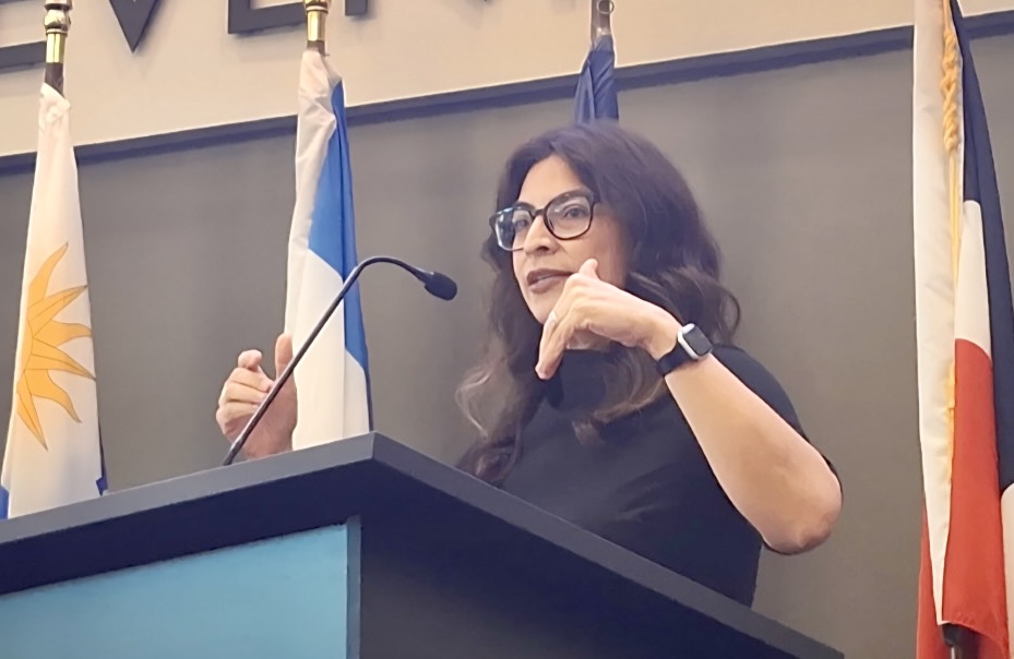 Larissa Mercado-López speaks at a podium during a University of the Incarnate Word presentation about Selena Quintanilla's cultural legacy.